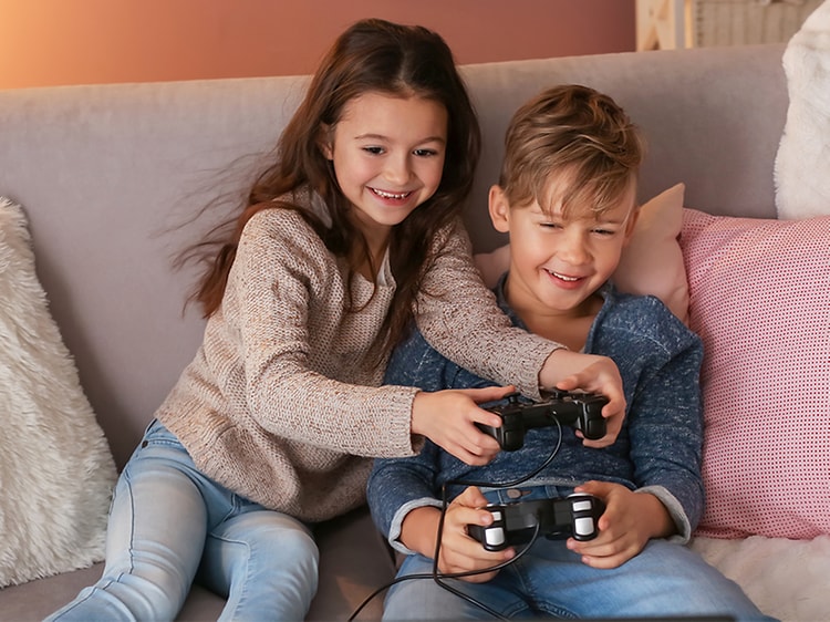 To barn som spiller TV-spill sammen i en sofa