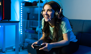 Kvinne med headset som sitter i sofaen og gamer