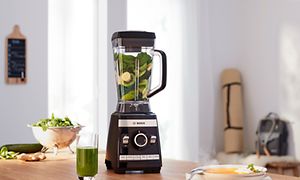 Bosch-blender fylt med grønne grønnsaker og frukt på en kjøkkenbenk