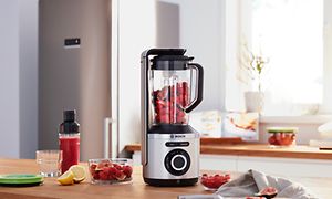 Bosch-blender fylt med jordbær stående på en kjøkkenbenk