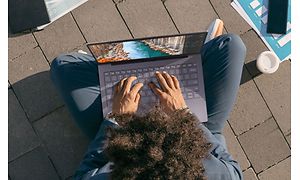 Mann sitter på bakken med Samsung Galaxy Book S i fanget