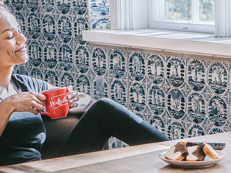 Kvinne drikker fra en kaffekopp og kaffemaskin på et bord