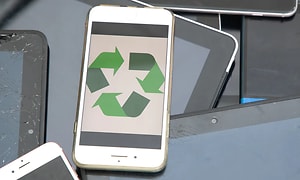 en hvit smarttetelefon med resirkuleringssymbol i grønt på skjermen