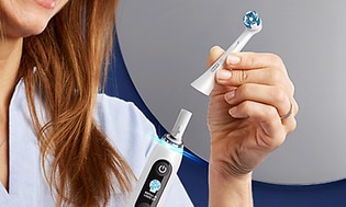 kvinne bytter børstehode på en Oral-B elektrisk tannbørste