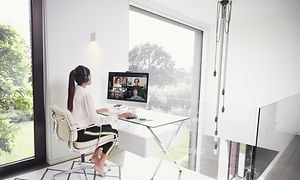 Woman working in home office using Jabra Evolve2 75 headset while attending Teams meeting