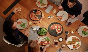 Personer ved spisebord som nyter pizza