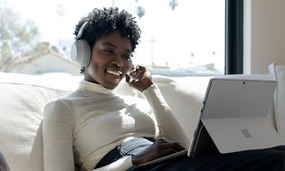 Surface Pro Lifestyle - Kvinne med hodetelefoner og Surface Pro på fanget