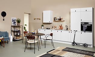 White EPOQ Core kjøkken i en åpen kjøkkenløsning, med sofa og spisebord
