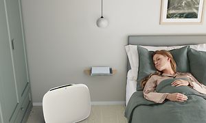 En dame som sover i sengen sin med en hvit Well A5 på gulvet ved siden av seg