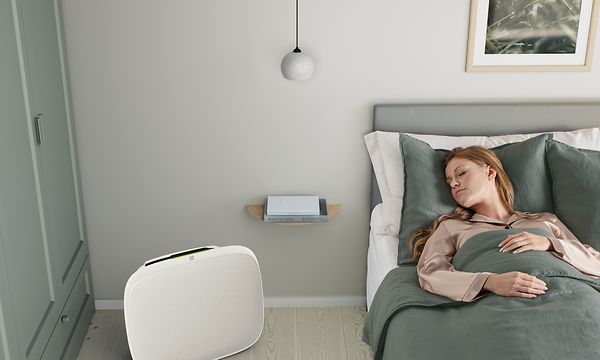 En dame som sover i sengen sin med en hvit Well A5 på gulvet ved siden av seg