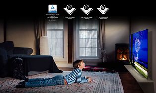 LG OLED TV i en koselig stua med et barn som ligger på gulvet foran den og ser på
