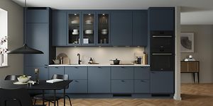 Epoq Trend Blue Grey kjøkken i en åpen kjøkkenløsning med integrert stekeovn, vitrineskap og spisebord