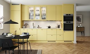 Mellow EPOQ Trend kjøkken i en åpen kjøkkenløsning med integrert stekeovn, glasskap og spisebord
