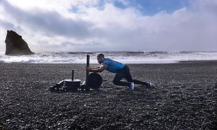 Garmin Fenix 6 på armen til mann som dytter vekter på strand