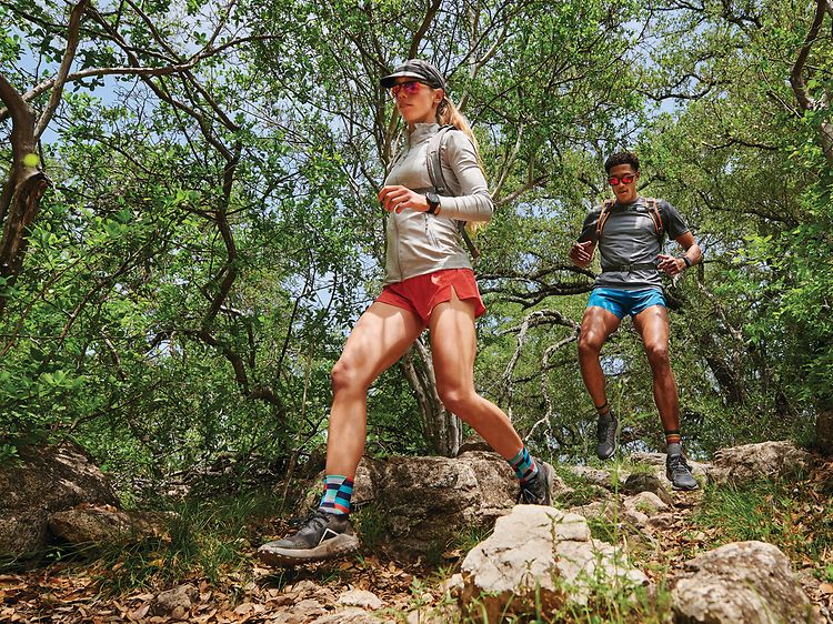 Garmin Fenix 7 på armene til kvinne og mann som løper i terrenget