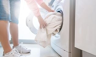 En person henter tørre håndklær ut av tørketrommelen.