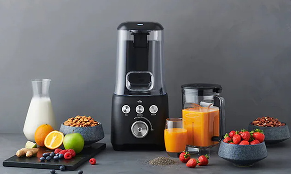 Frukt, melk og nøtter ved siden av en svart blender