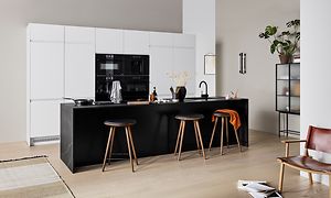 White EPOQ Integra kjøkken med en åpen kjøkkenløsning, med barstoler og en svart kjøkkenøy
