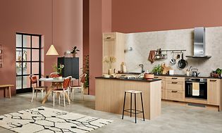 Beige wooden EPOQ Shaker kitchen in an open kitchen solution, with dining table, kitchen island and cooker hood