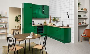 Green EPOQ Trend kjøkken i en åpen kjøkkenløsning med integrert stekeovn og kjøkkenbenk i tre og spisebord