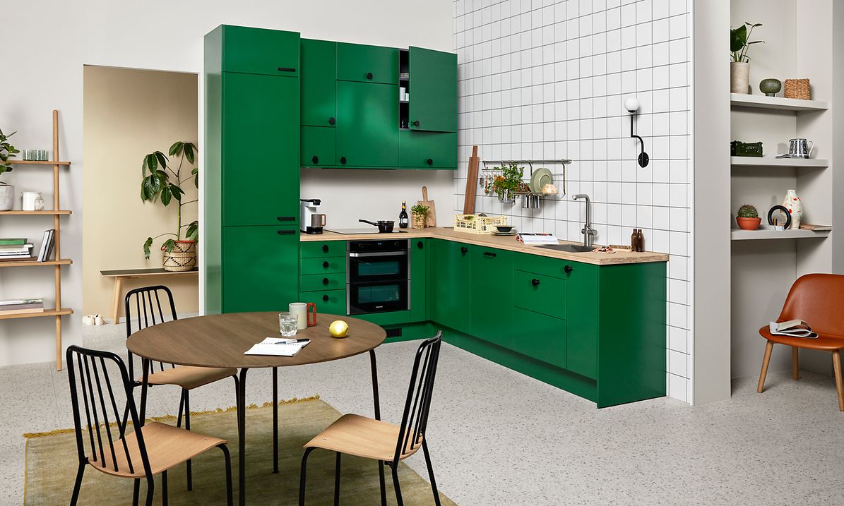 Green EPOQ Trend kjøkken i en åpen kjøkkenløsning med integrert stekeovn og kjøkkenbenk i tre og spisebord