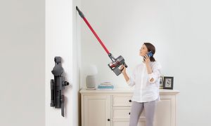 En kvinne som bruker Roborock trådløs stavstøvsuger for å rengjøre veggen