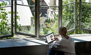 Kvinne jobber på en bærbar PC foran et åpent vindu