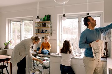 En familie på kjøkkenet tar ut rent servise fra oppvaskmaskinen.