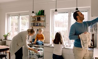 En familie på kjøkkenet tar ut rent servise fra oppvaskmaskinen.