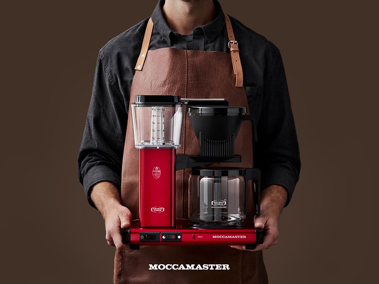 Mann i forkle som holder Moccamaster kaffetrakter