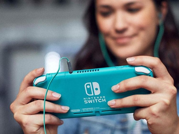 Smilende kvinne som spiller turkis Nintendo Switch Lite