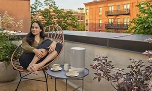 Kvinne på takterrasse med Sonos Move på kaffebord