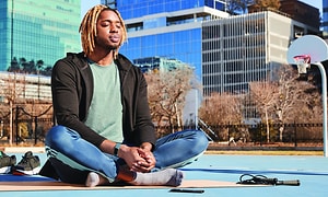 En mann mediterer på en yogamatte med Fitbit rundt håndleddet
