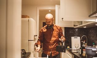 En mann holder en bestikkurv på kjøkkenet