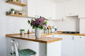 En vase med blomster står på kjøkkenbenken til et lite kjøkken