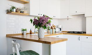 En vase med blomster står på kjøkkenbenken til et lite kjøkken