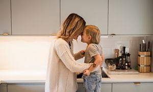 En mor og et barn klemmer hverandre på kjøkkenet