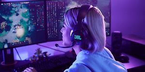 Jente som  bruker et JBL Quantum-headset og spiller DOTA