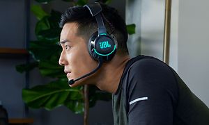 Ung mann som har på et JBL Quantum-headset og ser instenst mot noe