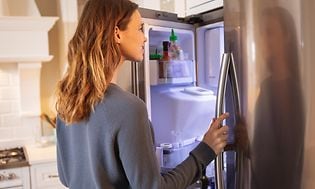Kvinne ser inn i kjøleskapet