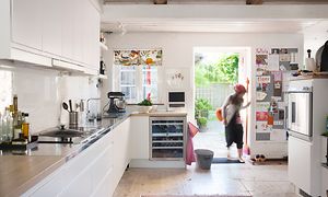 En person kommer inn kjøkkendøra på et hvitt kjøkken