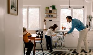 mann og barn tar ut oppvask fra en integrert oppvaskmaskin