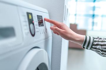 En person trykker på displayet og velger vaskeprogram på en vaskemaskin