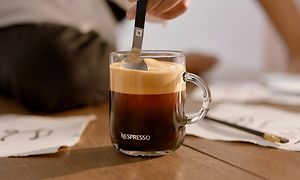 Hånd som rører kaffe i kaffekopp med en skje