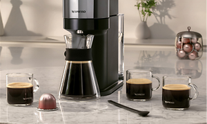 Nespresso Vertuo kaffemaskin og kaffekopper med kaffe ved siden av 