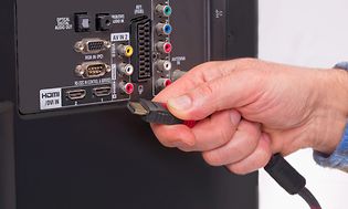 Hånd som kobler HDMI-kabel til TV