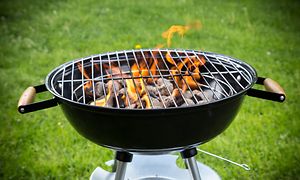 kullgrill med flammer på en grønn gressplen