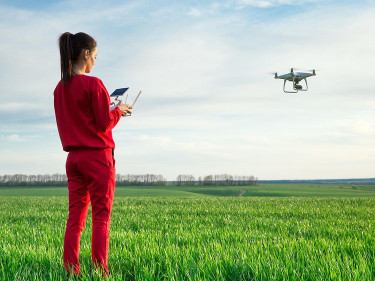 kvinne som flyr drone over et jorde