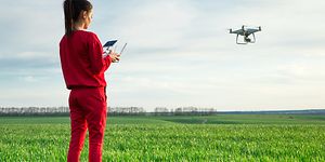 kvinne som flyr drone over et jorde