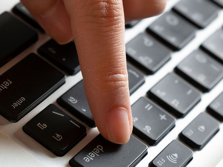Hånd som trykker på delete-knappen på et tastatur